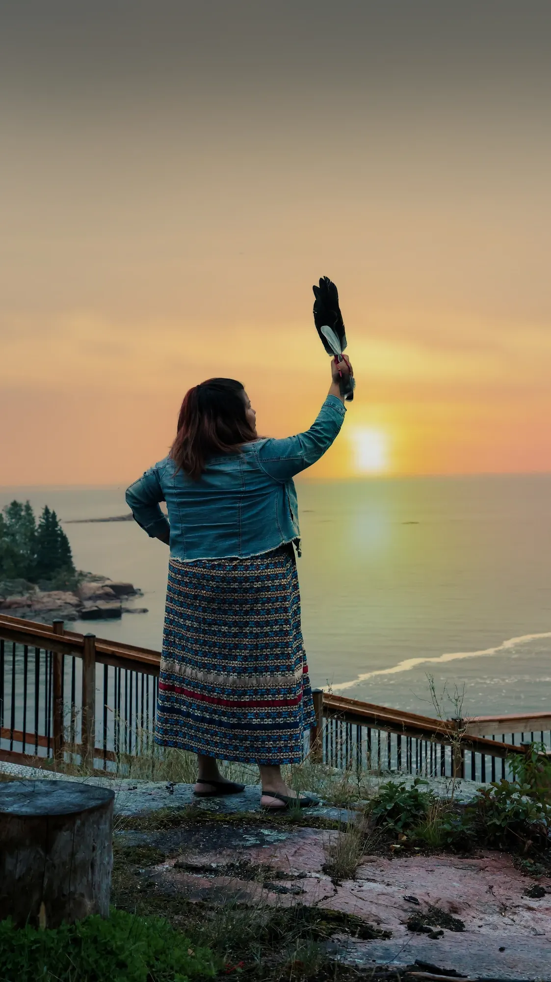Femme face au lac au coucher du soleil